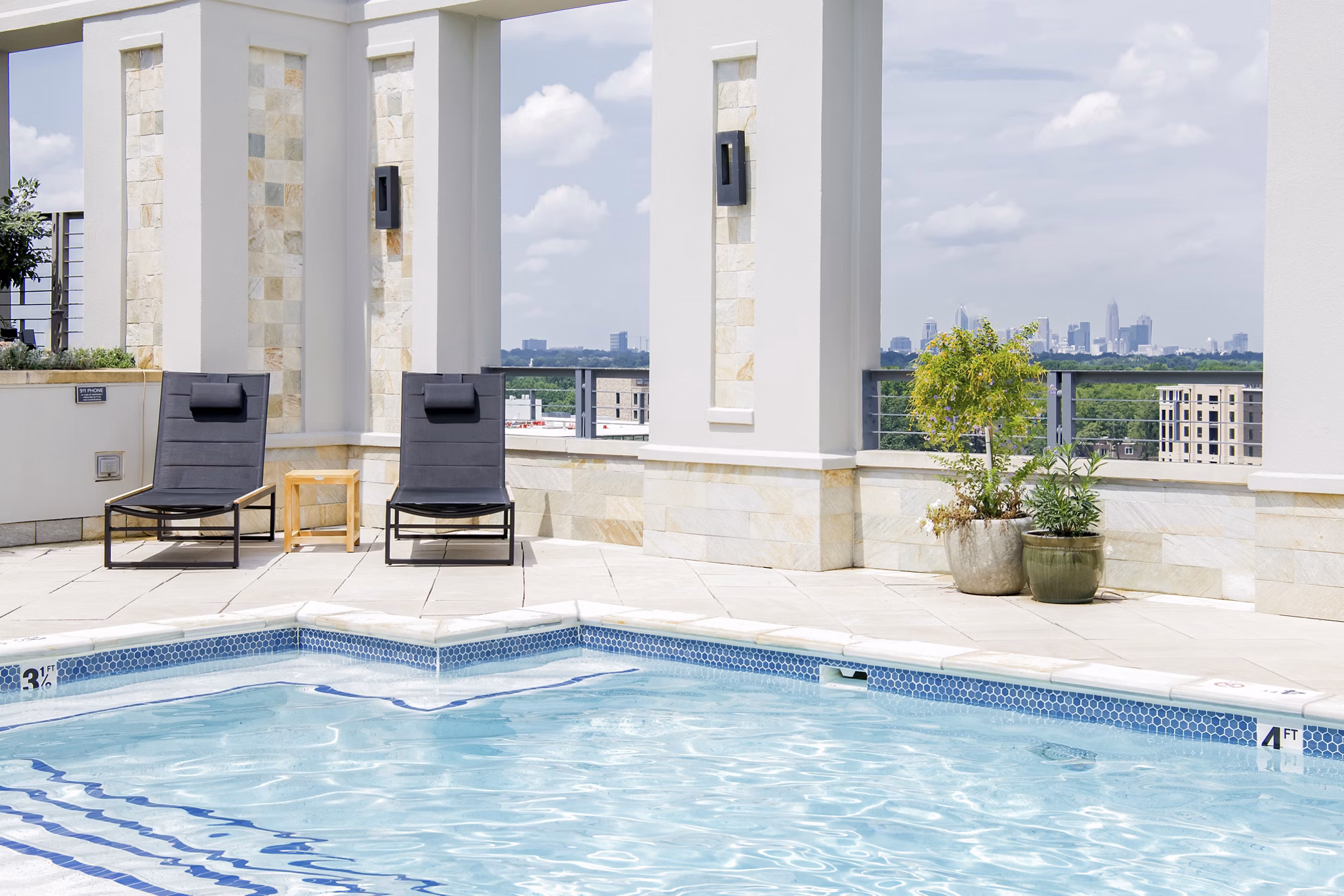 Outdoor pool with sun loungers and umbrellas at The Residence at SouthPark Apartments