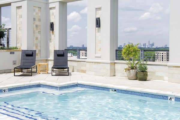 Outdoor pool with sun loungers and umbrellas at The Residence at SouthPark Apartments
