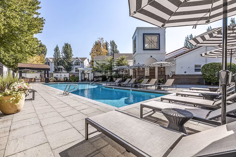 Resort-style pool at Avignon Townhomes Apartments with spacious sun deck and lush landscaping perfect for relaxation