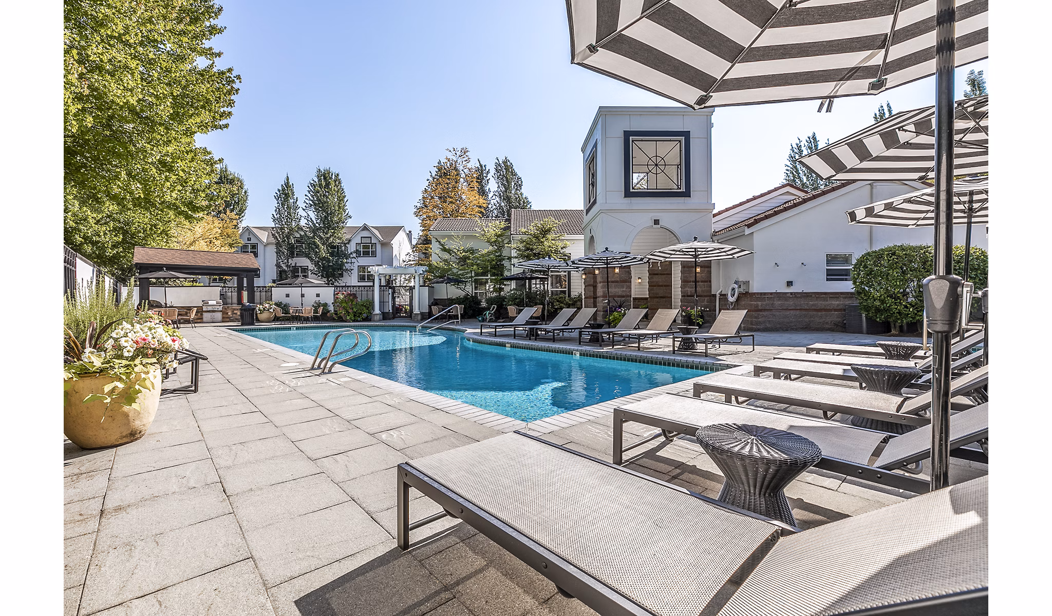 Resort-style pool at Avignon Townhomes Apartments with spacious sun deck and lush landscaping perfect for relaxation