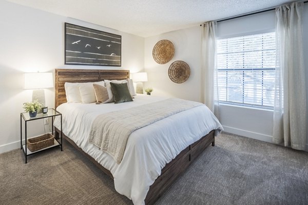Modern bedroom with elegant decor at Sage at Green Valley Apartments, featuring plush bedding and ample natural light in a luxury setting
