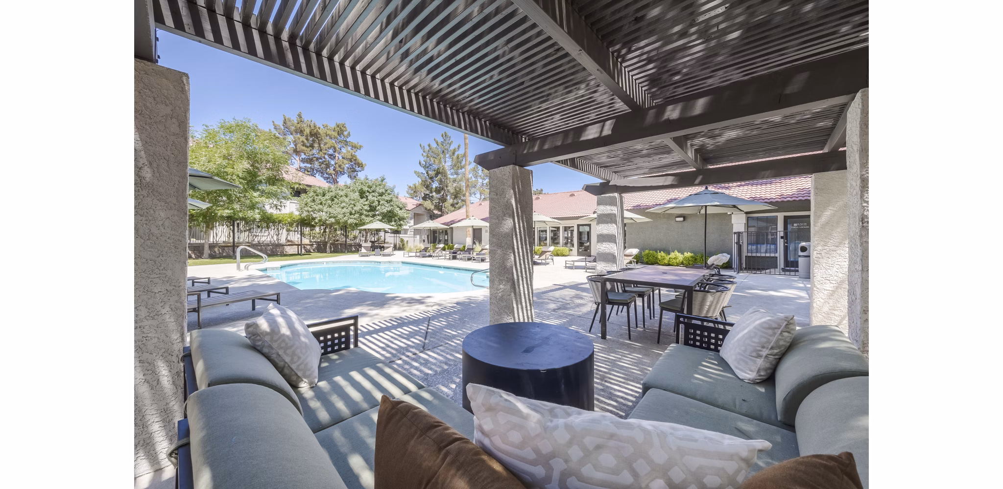 Outdoor pool and patio at Sage at Green Valley Apartments featuring lounge chairs and lush landscaping