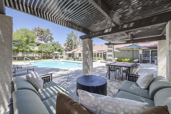 Outdoor pool and patio at Sage at Green Valley Apartments featuring lounge chairs and lush landscaping