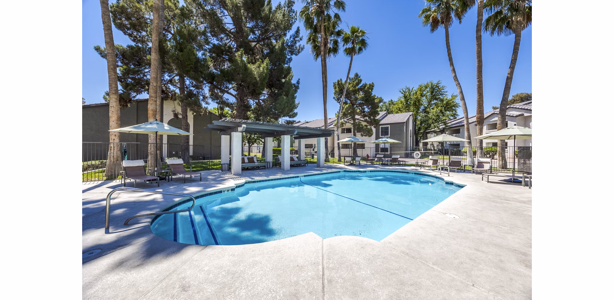 Resort-style pool surrounded by lush landscaping at Sage at Green Valley Apartments