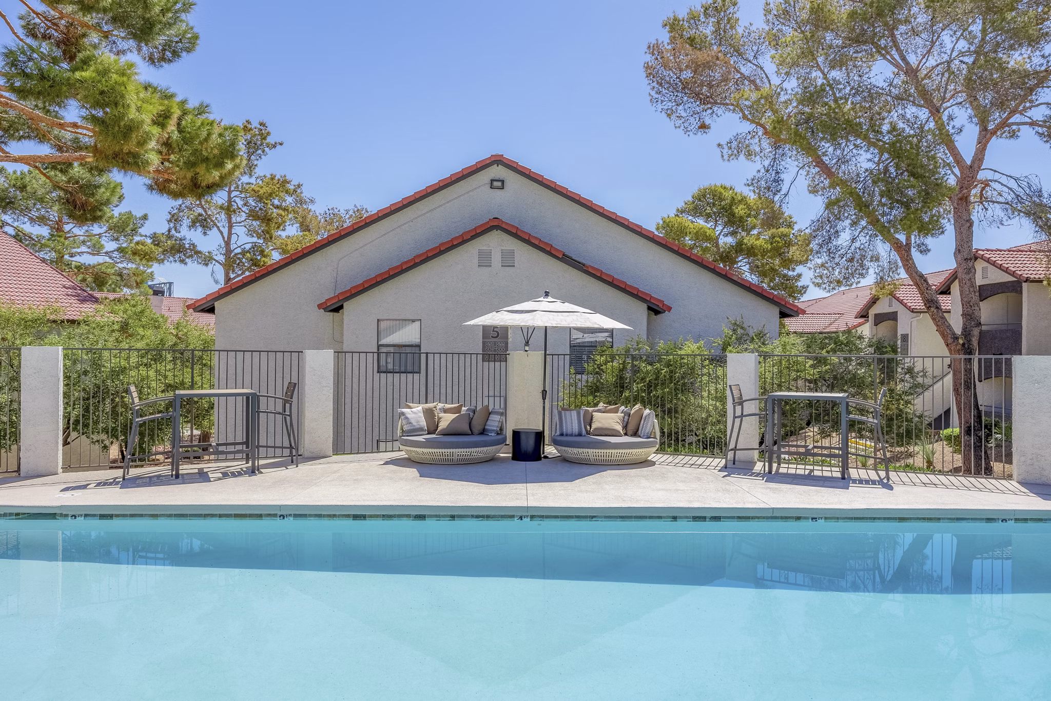 Poolside relaxation area at 5400 Vistas Apartments with lounge chairs and umbrellas, perfect for enjoying luxury outdoor amenities