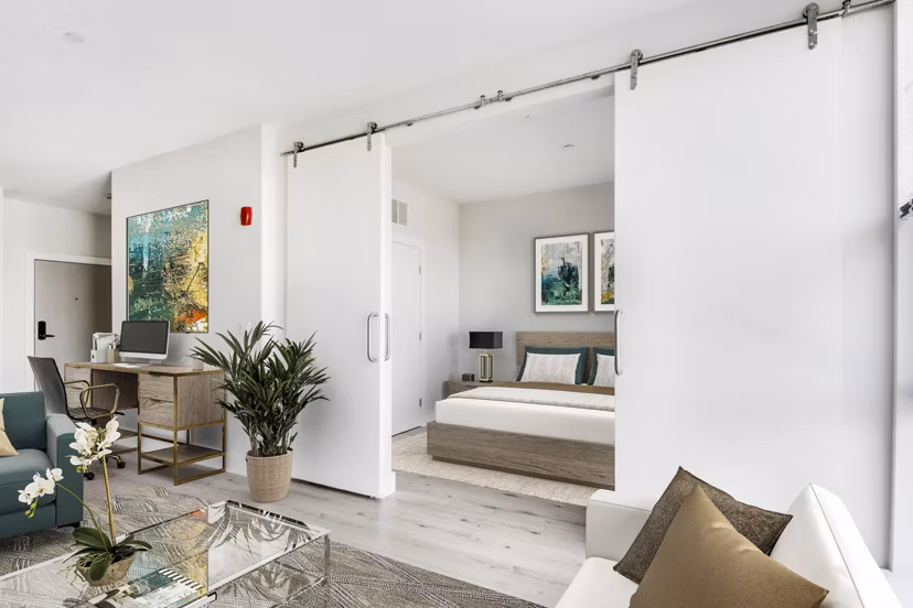 Cozy bedroom with large windows and modern decor at One Beachmont Apartments