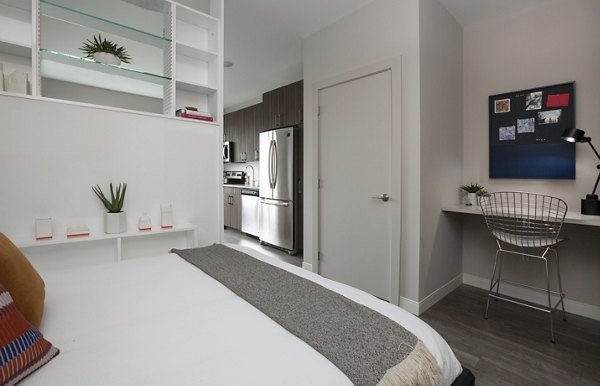 Modern bedroom with cozy decor at The Andi Apartments, offering luxurious living spaces and amenities in a vibrant urban setting