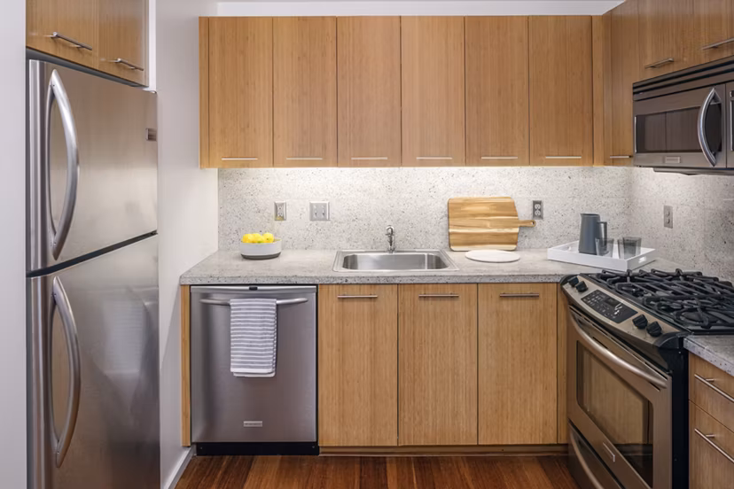 Modern kitchen with stainless steel appliances at Indigo at Twelve West Apartments