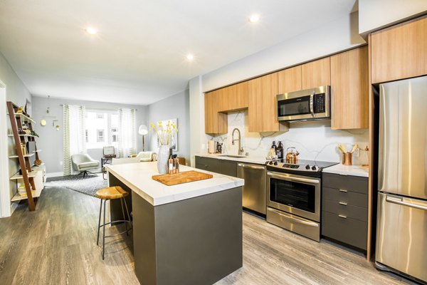 Modern kitchen with stainless steel appliances and quartz countertops at Fourth Street East Apartments