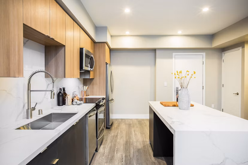 Modern kitchen featuring granite countertops and stainless steel appliances at Fourth Street East Apartments