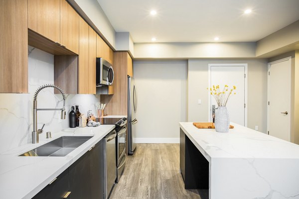 Modern kitchen featuring granite countertops and stainless steel appliances at Fourth Street East Apartments