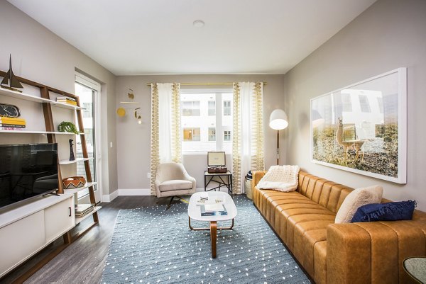 Modern living room with elegant furnishings and large windows at Fourth Street East Apartments