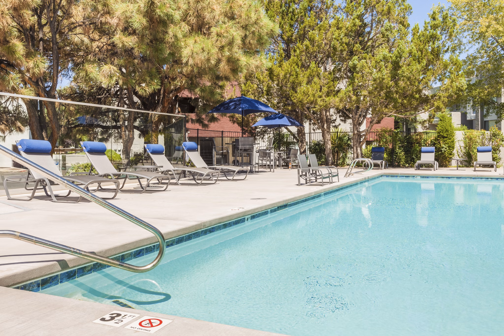 Resort-style swimming pool with lounge seating at The Village at Tierra Antigua Apartments