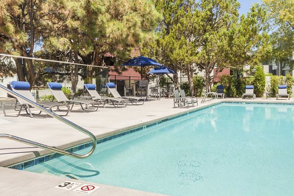 Resort-style swimming pool with lounge seating at The Village at Tierra Antigua Apartments