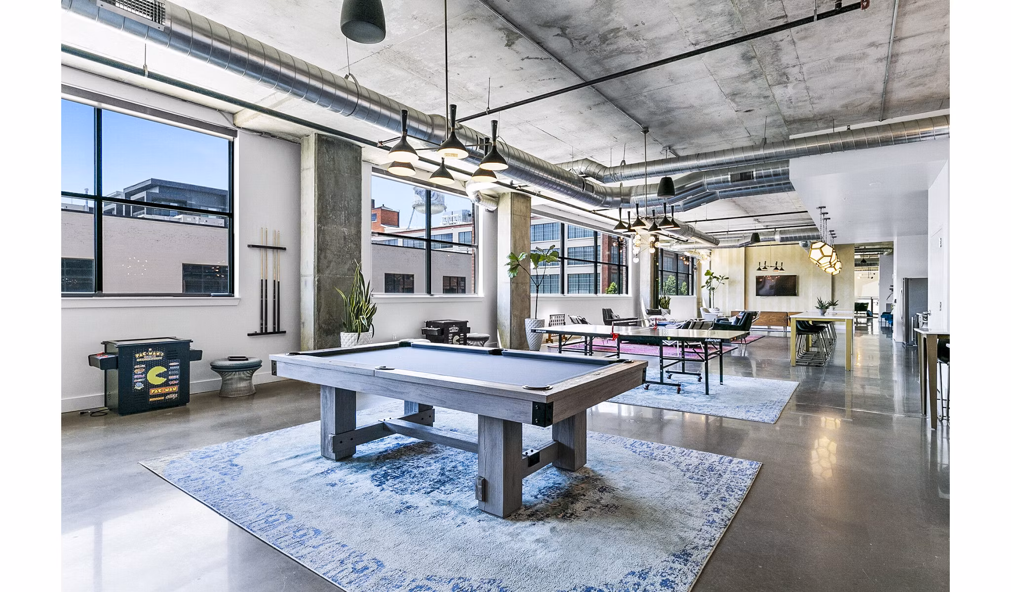 Clubhouse game room with pool and foosball tables at West Village Apartments, offering luxury living in a community-focused environment