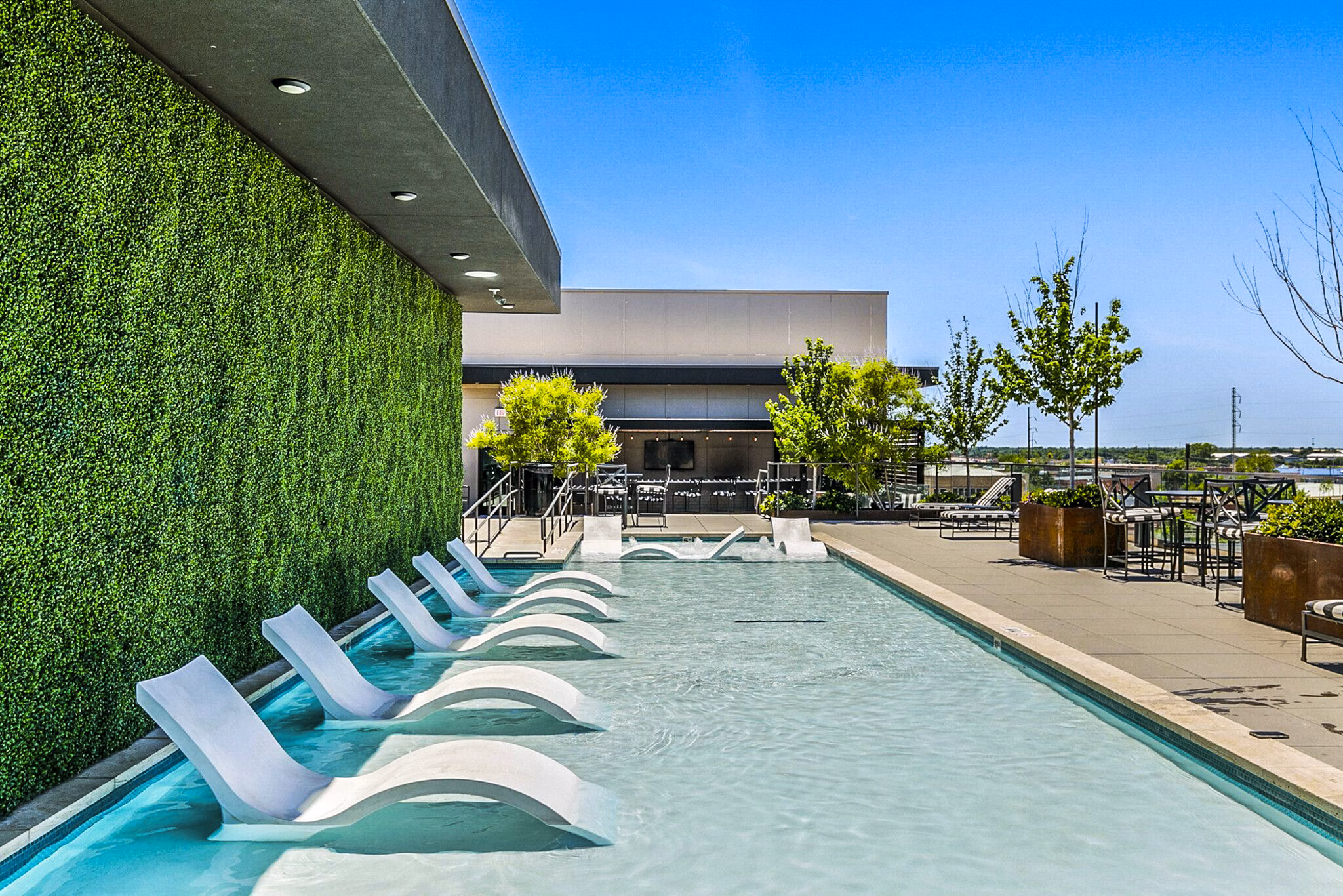 Outdoor pool with lounge chairs at West Village Apartments offering a relaxing space in a luxurious setting