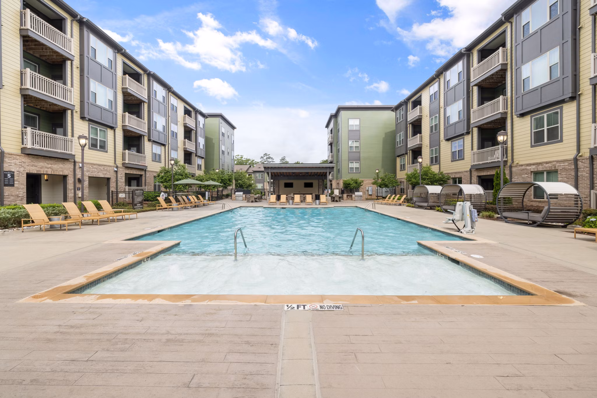 Resort-style pool at The Dakota Apartments featuring lush landscaping and comfortable loungers