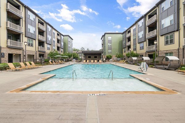 Resort-style pool at The Dakota Apartments featuring lush landscaping and comfortable loungers