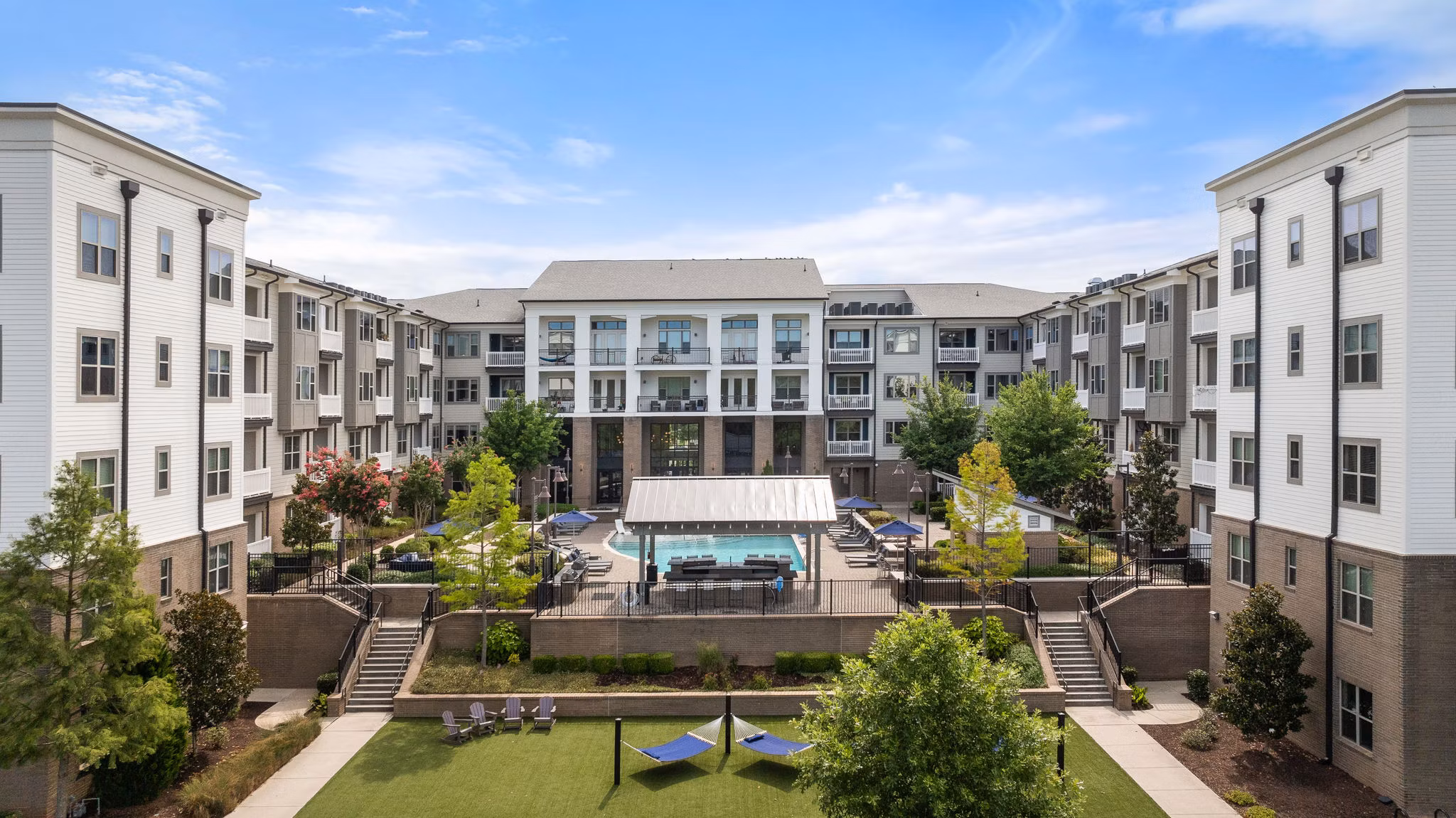 Luxury apartment complex with a central courtyard, pool, and lounge chairs