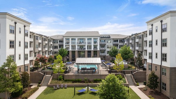 Luxury apartment complex with a central courtyard, pool, and lounge chairs