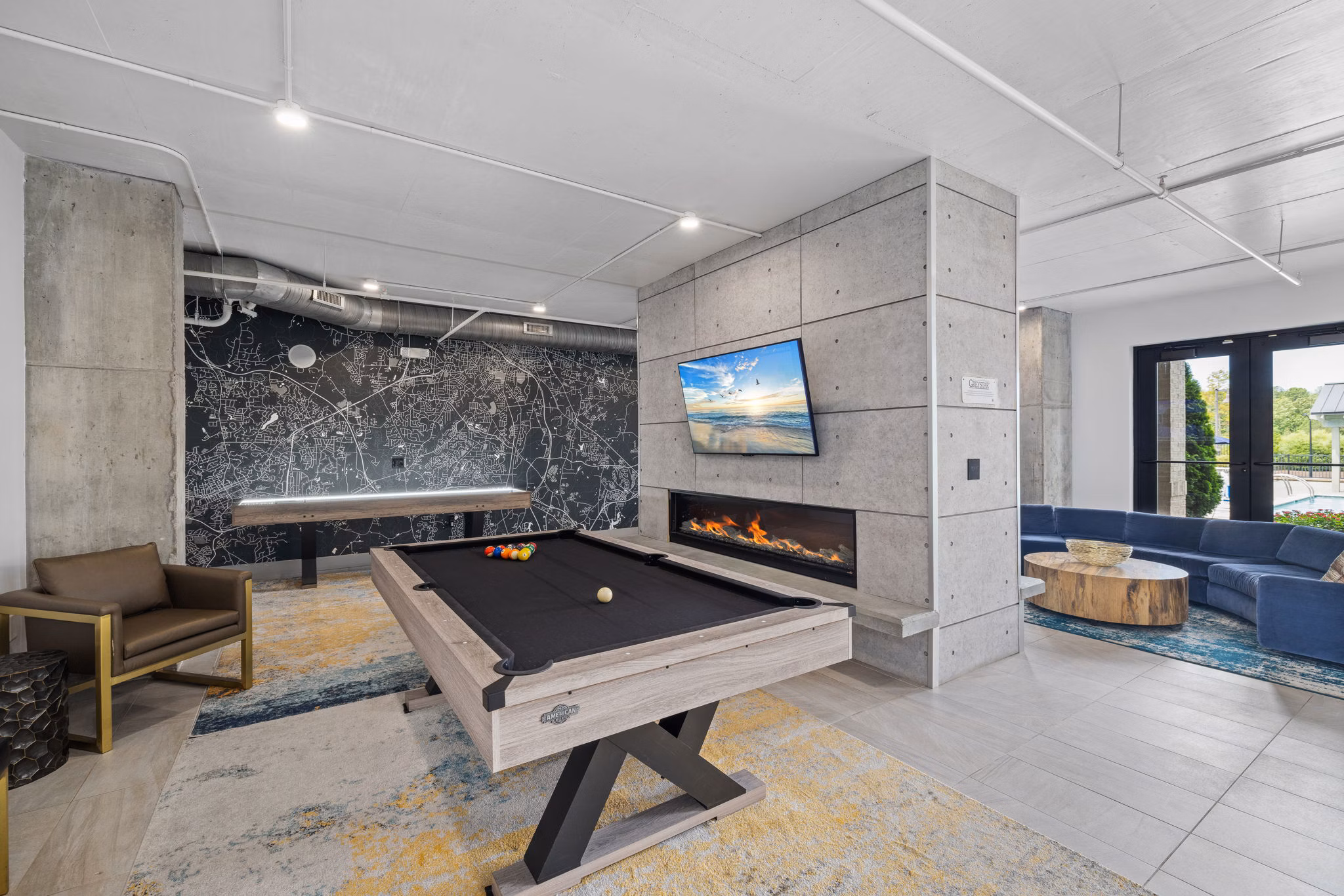 Modern game room with pool table, fireplace, and seating area in luxury apartments
