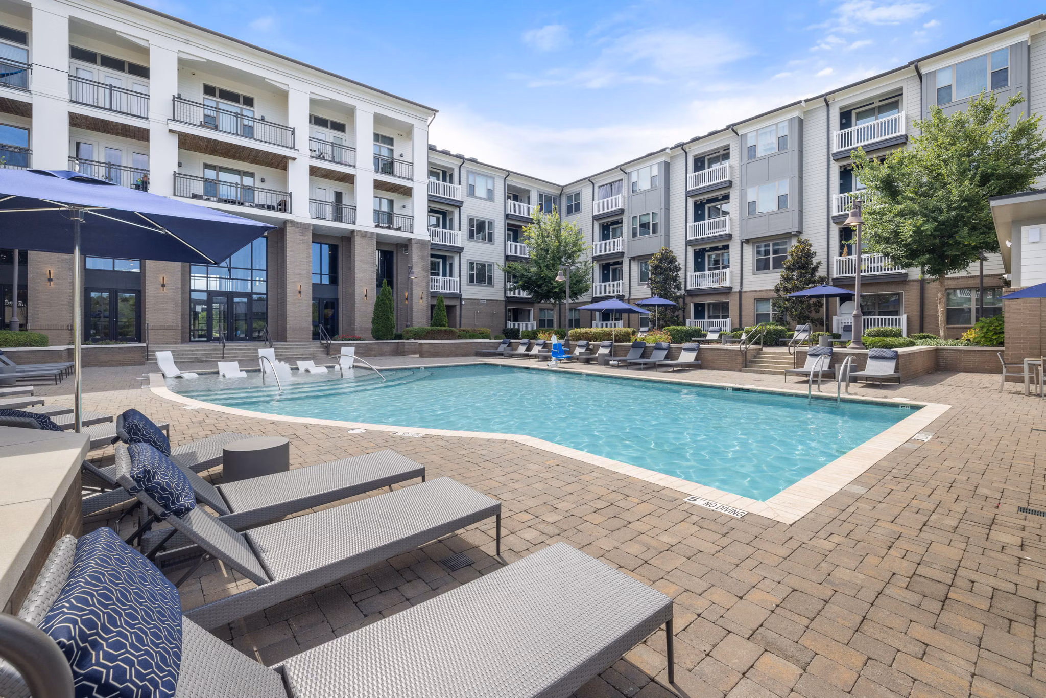 Expansive outdoor pool at Republic Flats Apartments with lounge seating and lush landscape