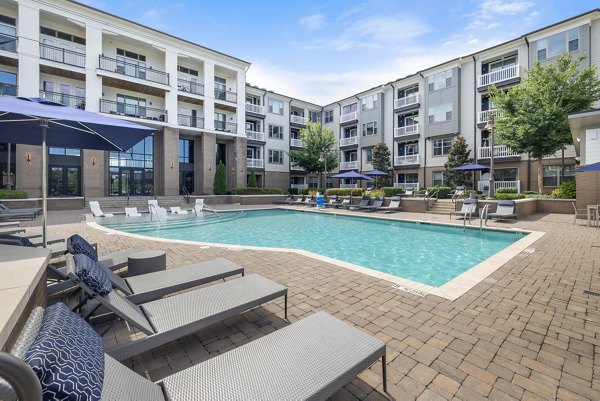 Expansive outdoor pool at Republic Flats Apartments with lounge seating and lush landscape