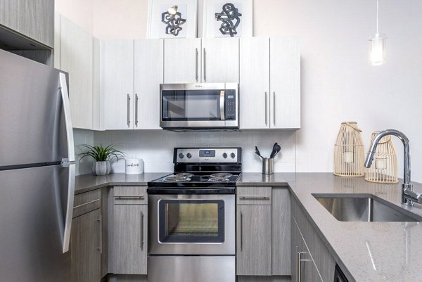 Modern kitchen with granite countertops and stainless steel appliances in Oak Street Station Apartments