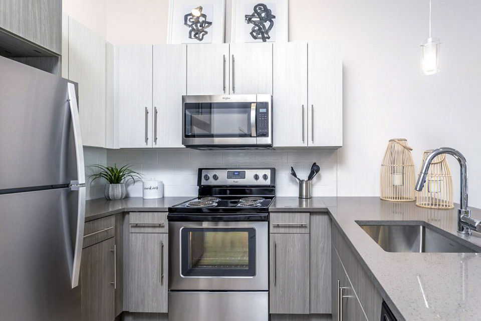 Modern kitchen with granite countertops and stainless steel appliances in Oak Street Station Apartments