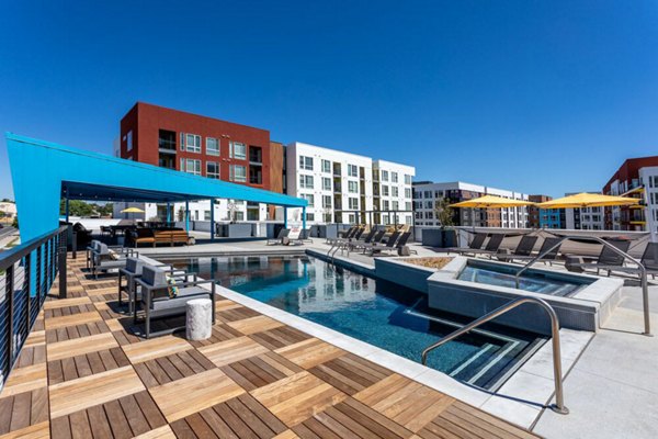 Oak Street Station Apartments: Relaxing poolside area with lounge chairs and lush landscaping