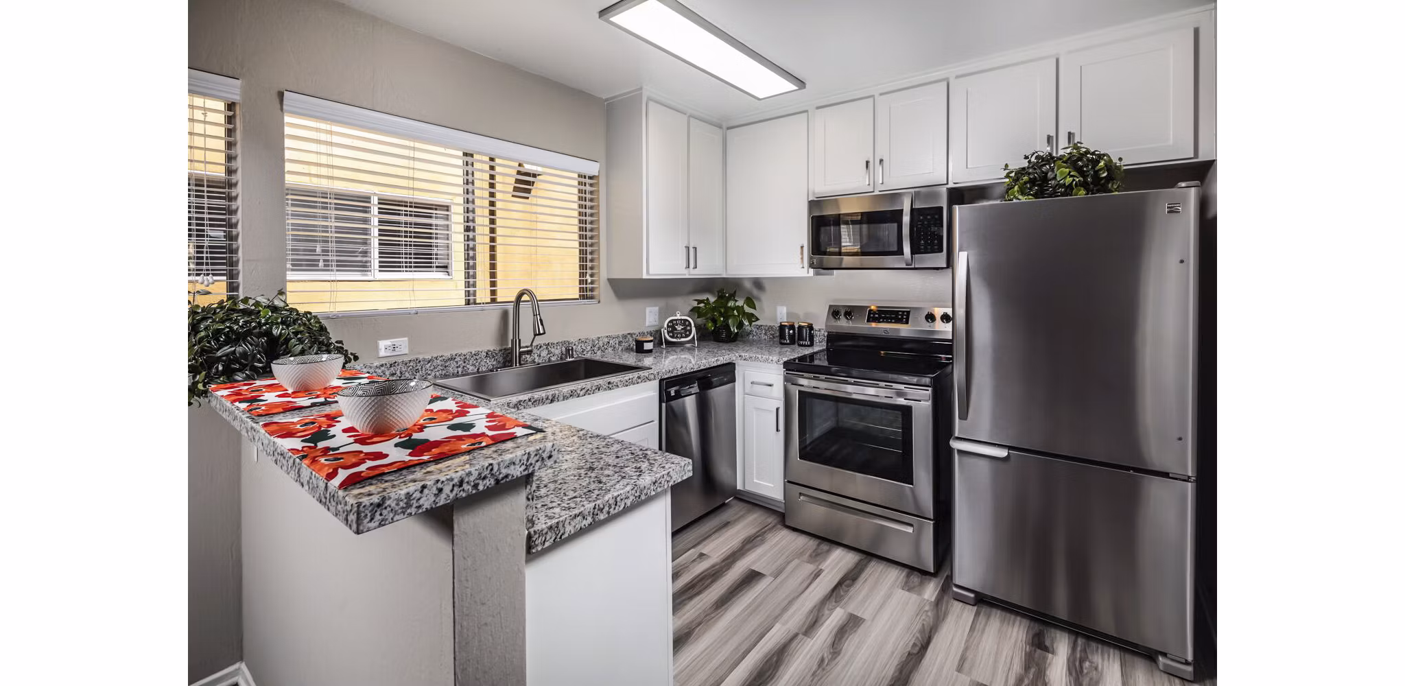 Modern kitchen with stainless steel appliances and granite countertops in Corte Bella Apartments