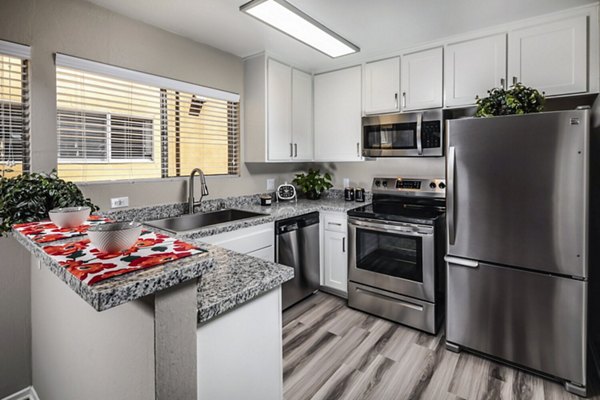 Modern kitchen with stainless steel appliances and granite countertops in Corte Bella Apartments