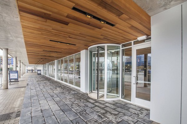 Elegant building entrance with glass doors and wooden ceiling at Harbor 1500 Apartments