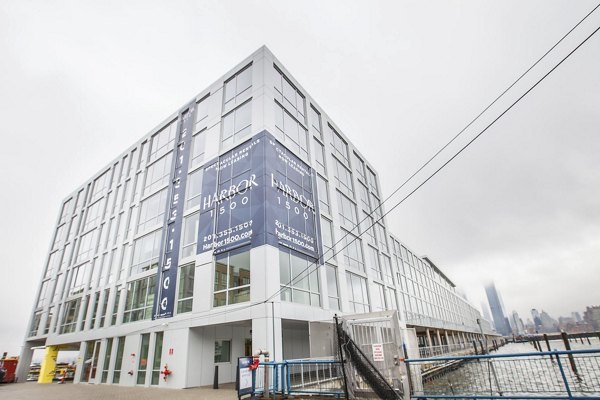 Harbor 1500 Apartments: Modern waterfront building with large banner under a cloudy sky