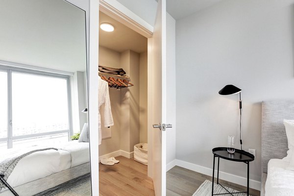 Bedroom featuring open closet, bed, and side table at Harbor 1500 Apartments Luxurious interior design in Greystar luxury apartments