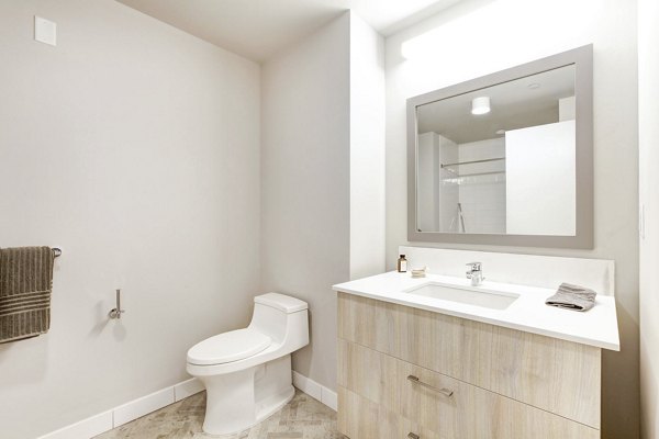 Minimalist bathroom with light wood vanity and large mirror at Harbor 1500 Apartments in Weehawken, featuring sleek design and modern fixtures