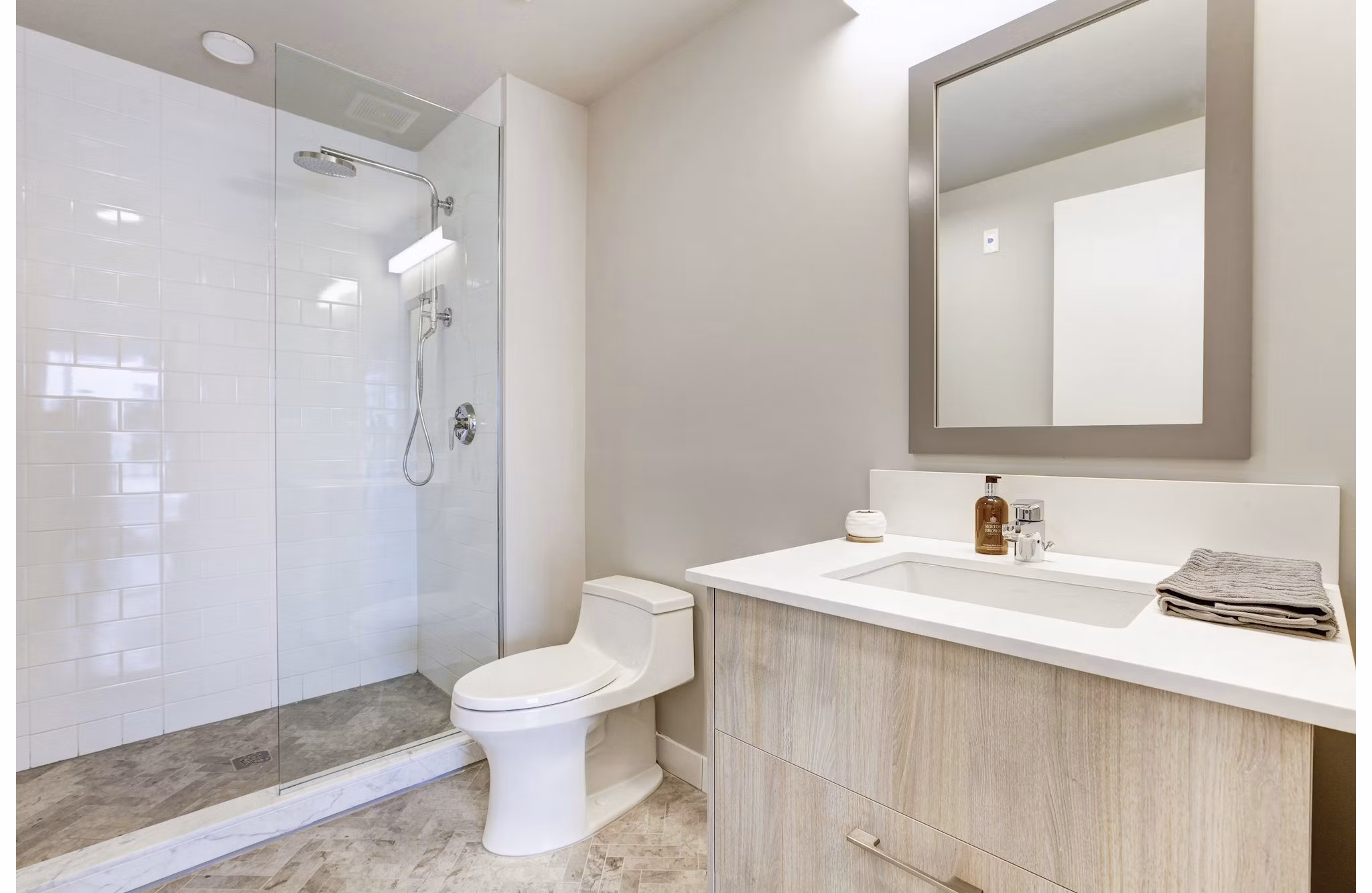 Minimalist bathroom with glass shower, toilet, and light wood vanity in Harbor 1500 Apartments, luxury living in Weehawken