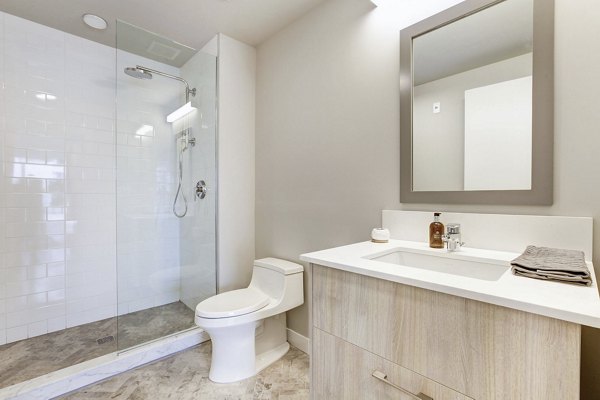 Minimalist bathroom with glass shower, toilet, and light wood vanity in Harbor 1500 Apartments, luxury living in Weehawken