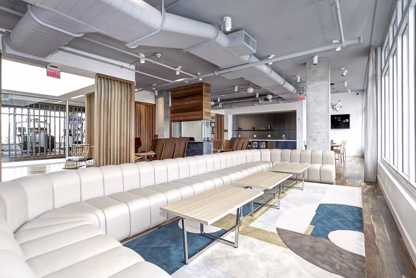 Modern lounge area with white sectional sofa and tables at Harbor 1500 Apartments, offering luxury living by the waterfront
