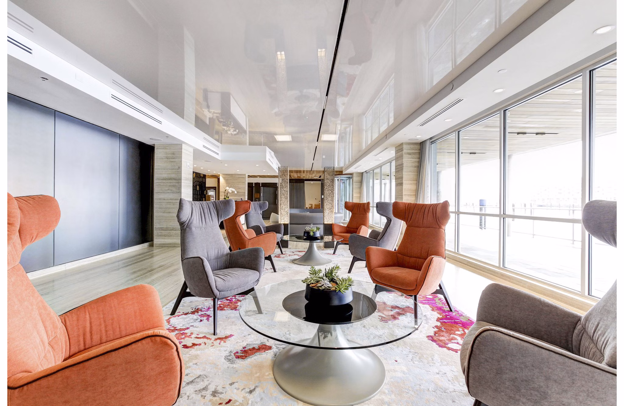 Bright lounge area with colorful chairs and glass tables at Harbor 1500 Apartments in New Jersey