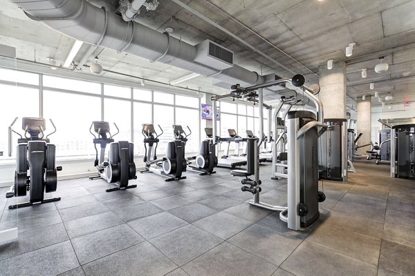 Spacious gym with exercise machines and large windows at Harbor 1500 Apartments