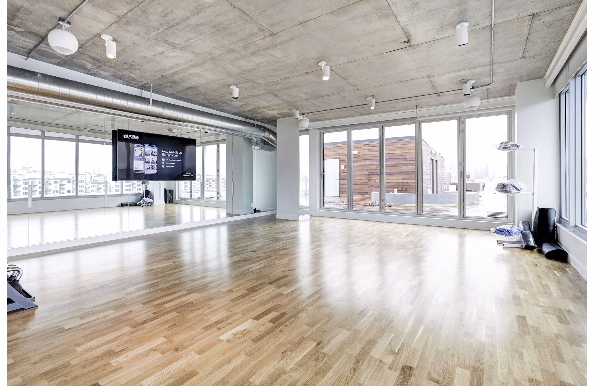 Spacious fitness studio with wooden floors and large windows at Harbor 1500 Apartments