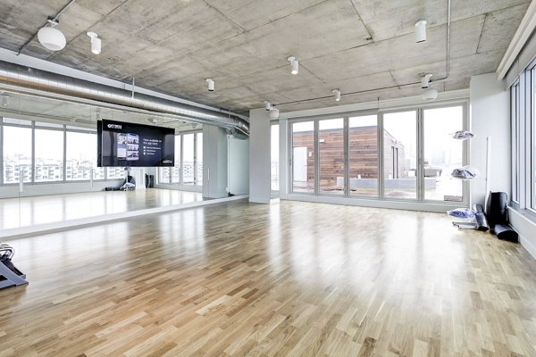 Spacious fitness studio with wooden floors and large windows at Harbor 1500 Apartments