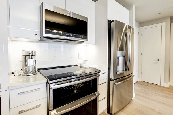 Sleek kitchen featuring stainless steel appliances and white cabinets at Harbor 1500 Apartments