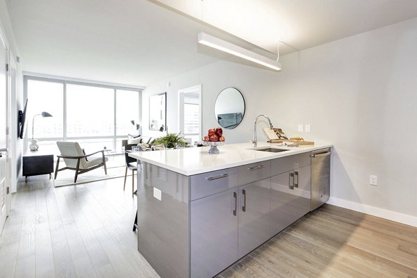 Bright kitchen with island, open living area, and large windows at Harbor 1500 luxury apartments