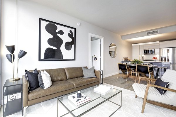 Spacious living room with stylish abstract art and dining area in Harbor 1500 luxury apartments, featuring modern design and open kitchen layout