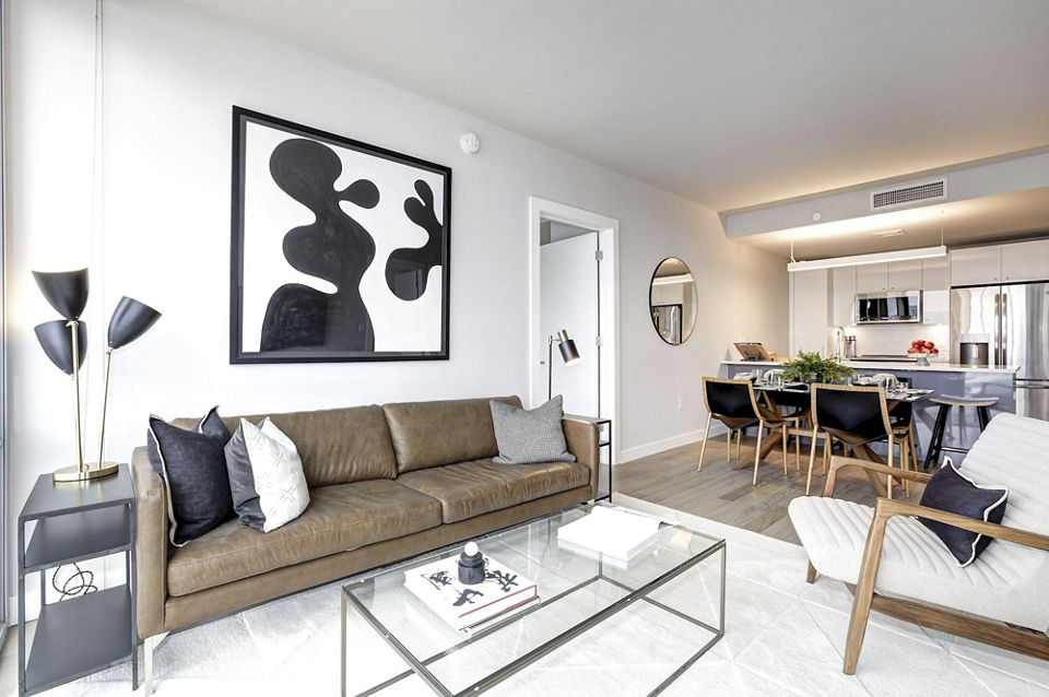 Spacious living room with stylish abstract art and dining area in Harbor 1500 luxury apartments, featuring modern design and open kitchen layout