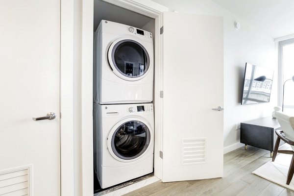 Compact closet with stacked washer and dryer in Harbor 1500 Apartments, offering convenient in-unit laundry for residents