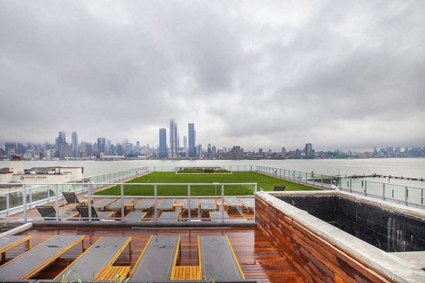 Rooftop terrace with seating and city skyline view at Harbor 1500 luxury apartments, featuring a green lawn