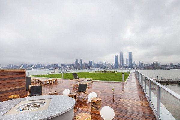 Rooftop deck with seating, fire pit, and city skyline view at Harbor 1500 Apartments